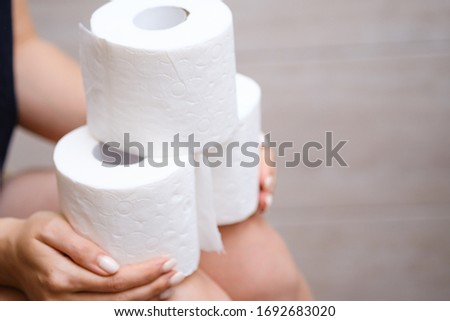 Woman holds many rolls of toilet paper representing panic buying during the coronavirus COVID-19 pandemic in 2020. preparation for quarantine and economic crisis due to coronavirus. Hygiene concept