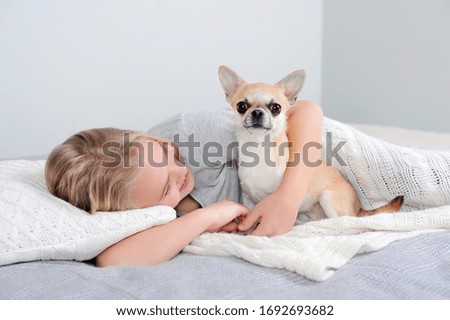 Girl staying in bed hugging her little puppy