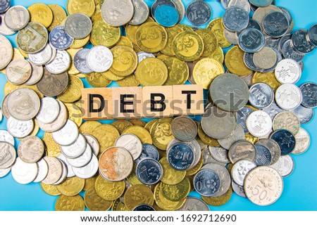 Coin with Wooden blocks text DEBT Business and finance concept.