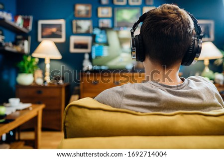 Adult gamer with headphones playing internet MMORPG cyber strategy online video game on computer gaming rig.Abstract virtual reality world.Spending time alone at home.Antisocial addiction disorder Royalty-Free Stock Photo #1692714004