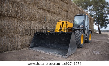 Tractor in Front of a Wall of Hay Bales