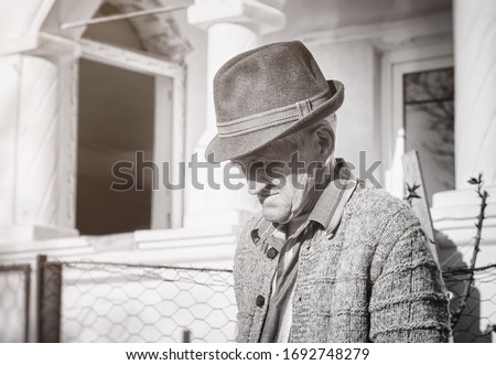 Portrait of a thoughtful senior man wearing hat, outdoor portrait picture. Black & white picture.