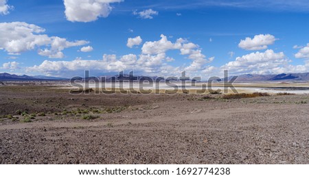 Panorama, looking north, of Grimshaw Lake, near Tecopa and south of Death Valley, as seen from Old Spanish Trail highway. Landscape dominated by a stony terrain and puffy white clouds.