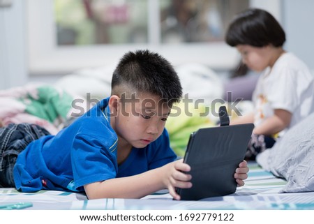 two children addicted tablet, asian child watching cartoon