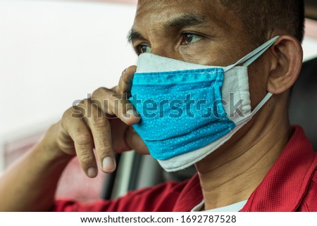 Thailand Close-up male face with a mask stacked two layers, white and blue inside the car so dismal.