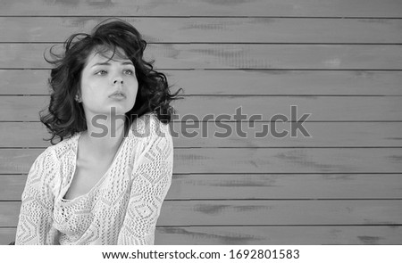 Romantic girl in a white openwork top looks at you. Pretty girl with curly hair posing in studio. Black and White Photography. Copy space for your text. 
