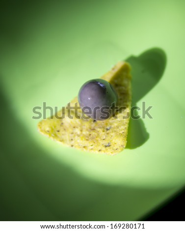 Doritos and olive on green plate