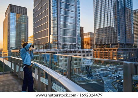 A young man is taking a picture of a group of buildings in the city.