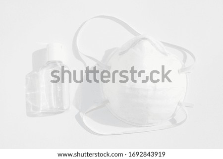 Hand sanitizer and face mask on white background.Protection during coronavirus pandemic. 