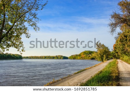 View of Missouri River with dirt road in foreground and colorful hills in the background; fall in Missouri, Midwest Royalty-Free Stock Photo #1692851785