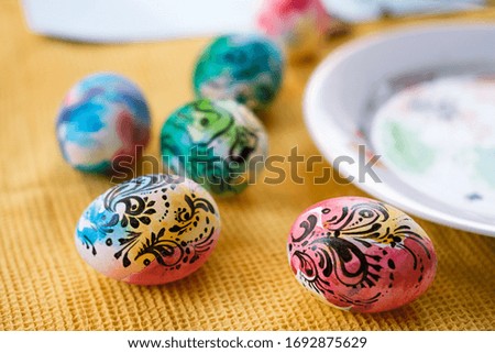 Colorful Easter eggs with a graphic pattern are lying on the table. Palette, tubes of paint, creativity. Preparing for the holiday. Easter concert.