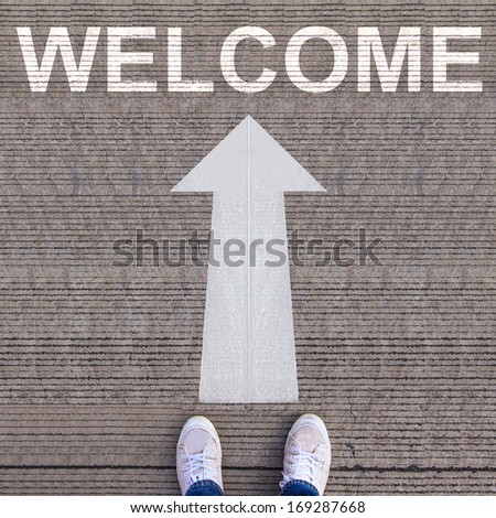 Pair of shoes standing on walkway with arrow and WELCOME