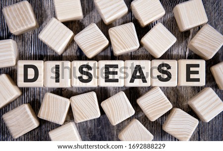 DISEASE - medical concept, text on wooden cubes and many cubes around on a dark background