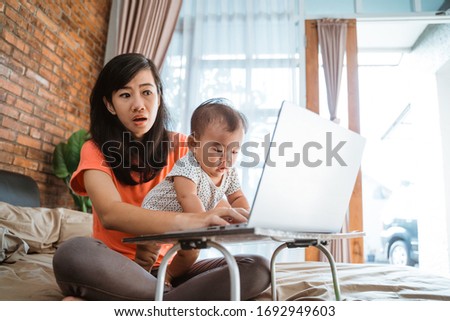 asian young woman working while taking care of her children at home