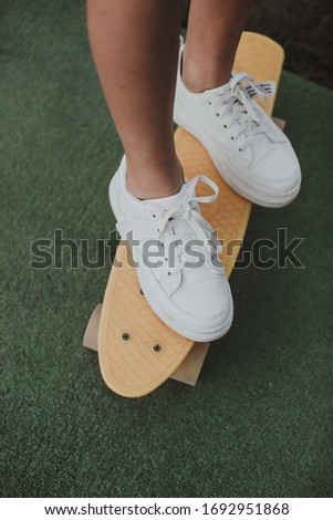 a little girl stands with her feet on a yellow skateboard
