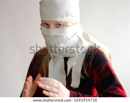 funny photo - quarantined due to an epidemic of coronavirus. girl in a mask from toilet paper posing on a gray background.