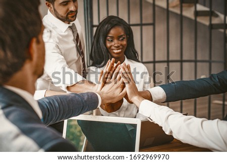 High Five In Agreement Sign, Teamwork Of Cheerful Multi-Ethnic Business Team Join Their Hands Together Sitting Around Office Desk At Meeting, Toned Image