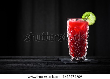 raspberry cocktail on black wooden bar with black background
