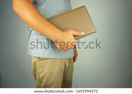 man wearing grey shirt and brown trouser holding brown book. white background.