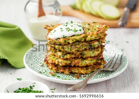 Zucchini fritters, vegetarian zucchini pancakes, served with fresh herbs and sour cream. Royalty-Free Stock Photo #1692996616