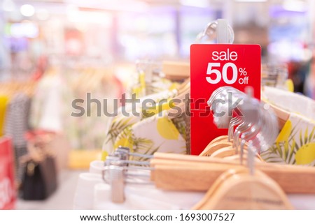 Red sale sign 50% discount on clothing rack in modern shopping mall or department store with copy space. Retail shop promotional event, new product discount, or business marketing advertising concept