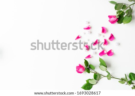 Pink, white, green flat lay: Pearls, pink rose petals, on white bright background. Beautiful set up. Top view, copy space, mock up. 