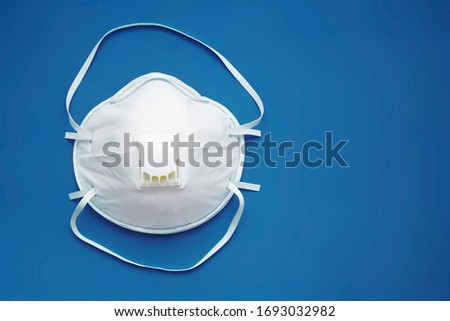 White face medical mask against virus, flu and coronavirus isolated on blue background. Protective respirator with valve. Royalty-Free Stock Photo #1693032982
