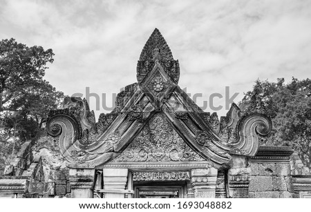 A black and white photo of the carved sandstone roof of the temple of Banteay Srei, a Hindu temple dedicated to the god Shiva, near Angkor Wat in Cambodia.