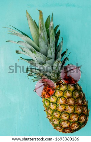 side view of pineapple with glasses on it on blue background