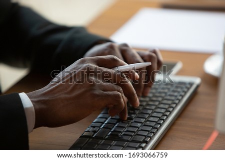 Typing text, close up. African-american entrepreneur, businessman working concentrated in office. Looks serios and busy, wearing classic suit. Concept of work, finance, business, success, leadership.