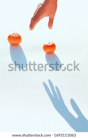 Artistic image of a human hand in an attitude of picking some oranges with their shadow