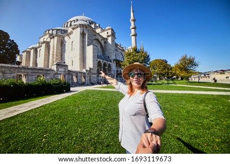Follow me. A woman tourist in a hat leads her friend to the Turkish mosque Suleymaniye, Istanbul, Turkey. Travel and religion concept.