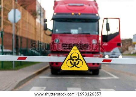 Truck standing at the barrier with a virus warning sign, Coronavirus containment concept
