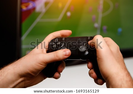 Man playing computer football or soccer game at home. Console controller in hands.
