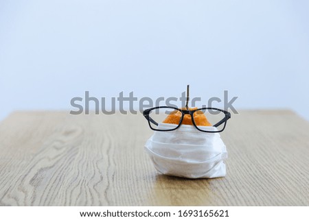 A fruit on a wooden table wearing a disposable medical mask