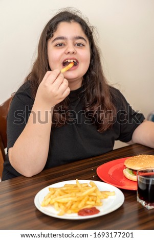 Young girl eating french fries and hamburger