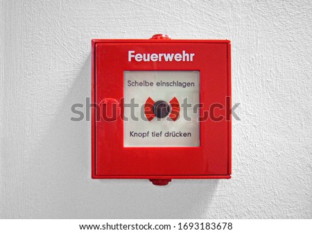 German red fire detector with the wording:
Fire Department,
Hit the disc,
Press the button deeply,