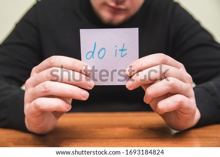 A man holds piece of paper saying "Do it"