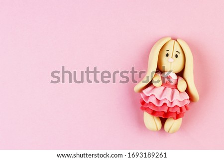 Plasticine Easter Bunny on a pink background. cute Bunny in a beautiful dress