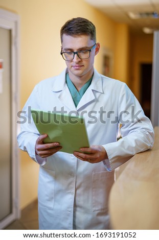 Portrait of a doctor or medical specialist. Vertical photo. Man in scrubs Hospital corridor background. Closeup.