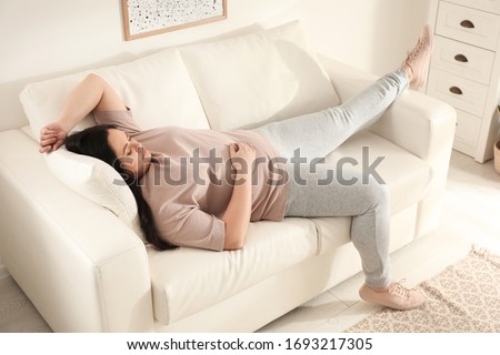 Lazy overweight woman sleeping on sofa at home Royalty-Free Stock Photo #1693217305