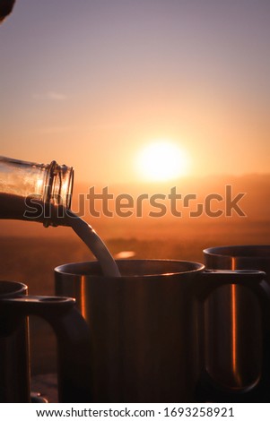 Milk being added to coffee before the african sunrise.
