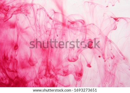 streaks of red paint dissolve in water. Smoke, a witch's potion, the texture of flares. Abstract background, texture.