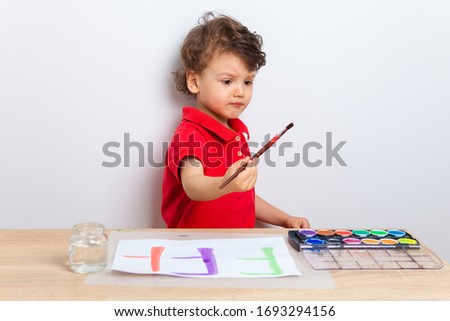 stay with your child at home. what to do with the preschooler during quarantine of the coronavirus. The child sits at a table and draws with a brush with paints