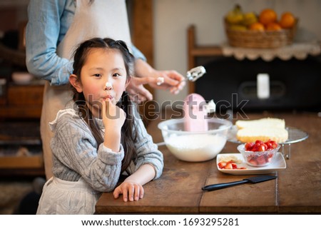 Mother and daughter making cake at home