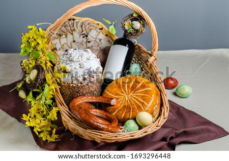 Basket with pie, sausage, wine, Easter cake, poppy seed roll, eggs