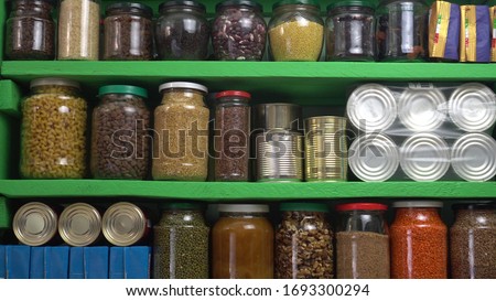 Food Stock Storage Shelf. Stocked home pantry ready for coronavirus quarantine and self-isolation. Long storage foods, drinks, supplies. Dry beans, rice, pasta, nuts, seeds, canned goods and vegetable