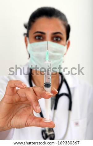 Beautiful Turkish doctor / nurse with hypodermic syringe that is being filled with vaccine