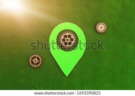 Green geolocation sign, wooden gears on a green background. Location detection mechanism.