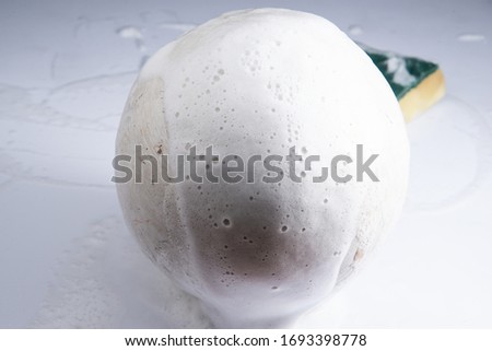 cleaning white sphere by yellow green sponge on acrylic background